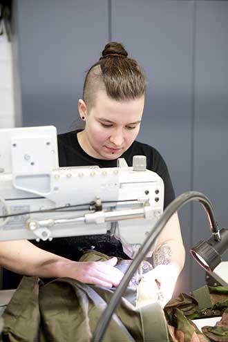 Maria Lehtonen korjaamassa armeijan erityisvarusteita ompelukoneella.