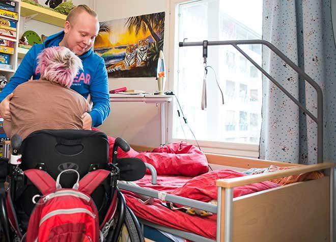 avustaja auttaa pyörätuolista