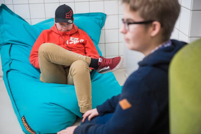 Sisävälitunnilla osa oppilaista kuuntelee musiikkia erkkerin säkkituoleilla.