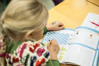 Oppilas tekee matematiikan tehtäviä kirjasta.