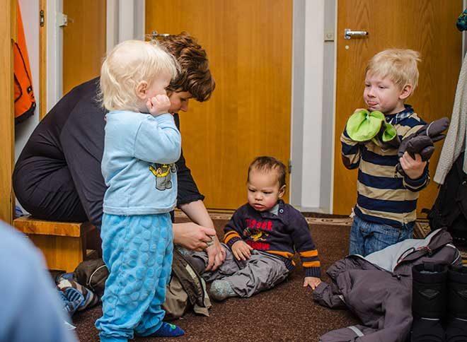 nainen pukee lapsille ulkohaalareita