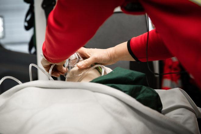 En syremask placeras på övningsdockan i ambulansen.