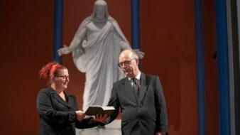 Maria och Christer Viksten läser i psalmboken framför Kristusstatyn i Lovisa kyrka.