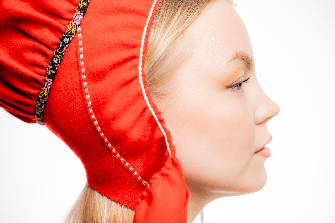 Nuori nainen Miisa Nuorgam sivuprofiilissa, päässä on punainen saamelaishattu.