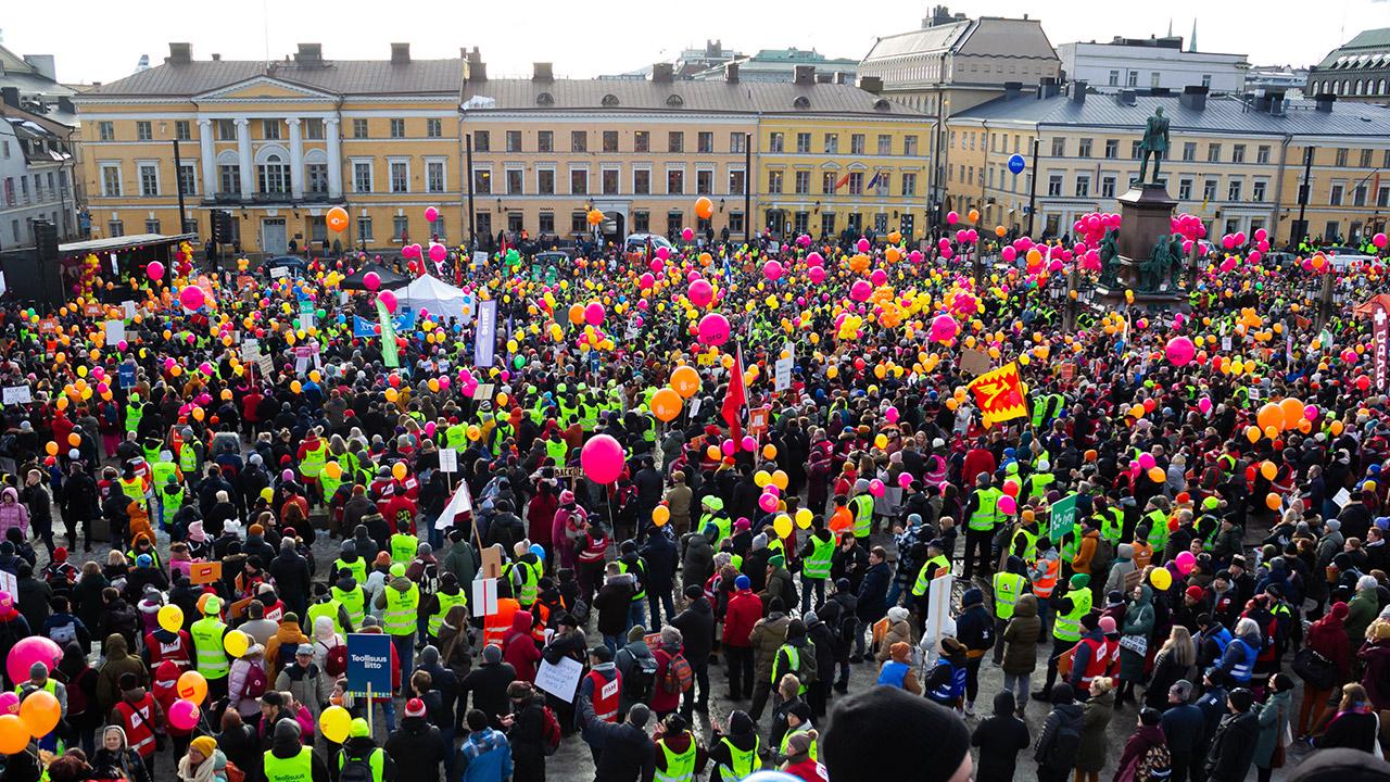 En stor skara människor med ballonger och skyltar på Senatstorget i Helsingfors.