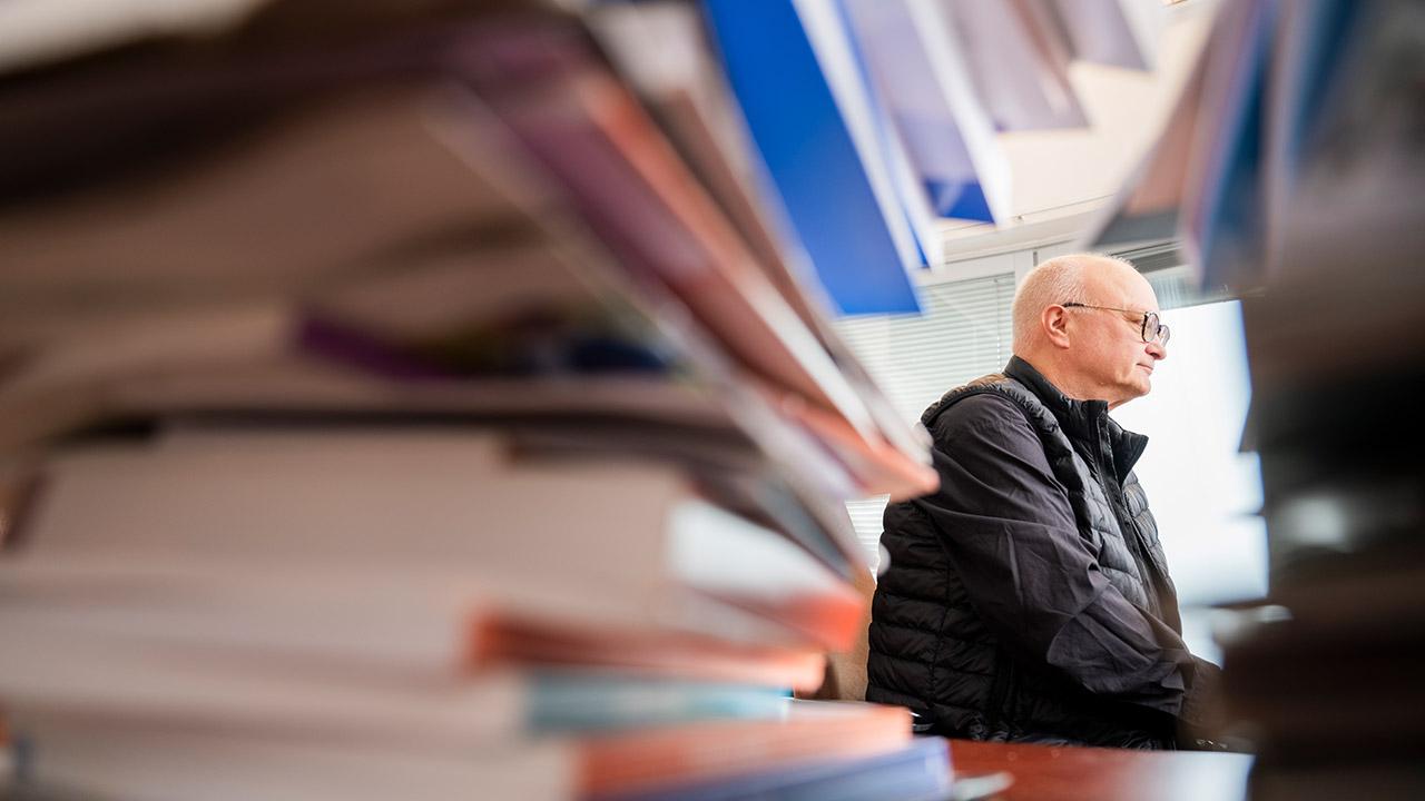JHL:n puheenjohtaja Håkan Ekström istuu työpöydän ääressä, etualalla kirjoja.