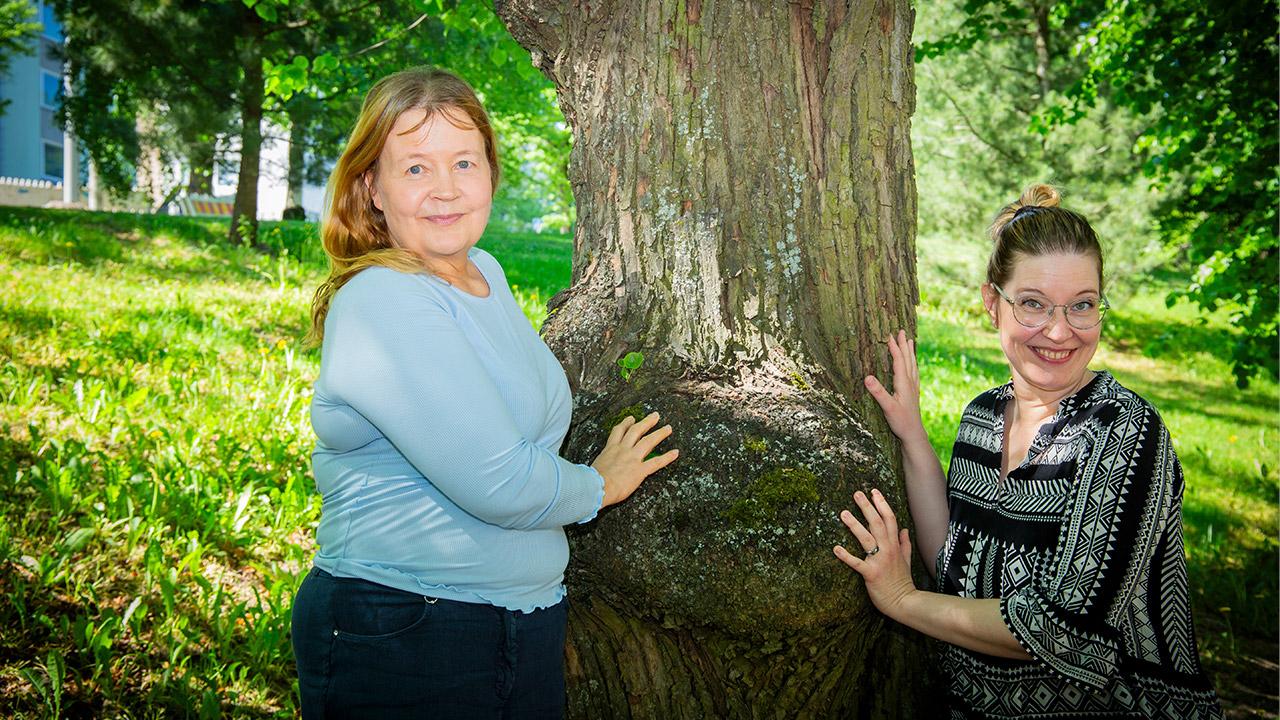 Nuorisotyöntekijät Suvi Lappalainen ja Reetta Möller nojaavat puuhun.
