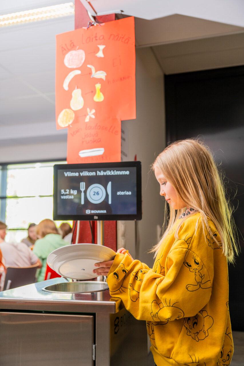 Lapsi punnitsee hävikkiruokaa Ollikkalan koulun ruokalassa Salossa.