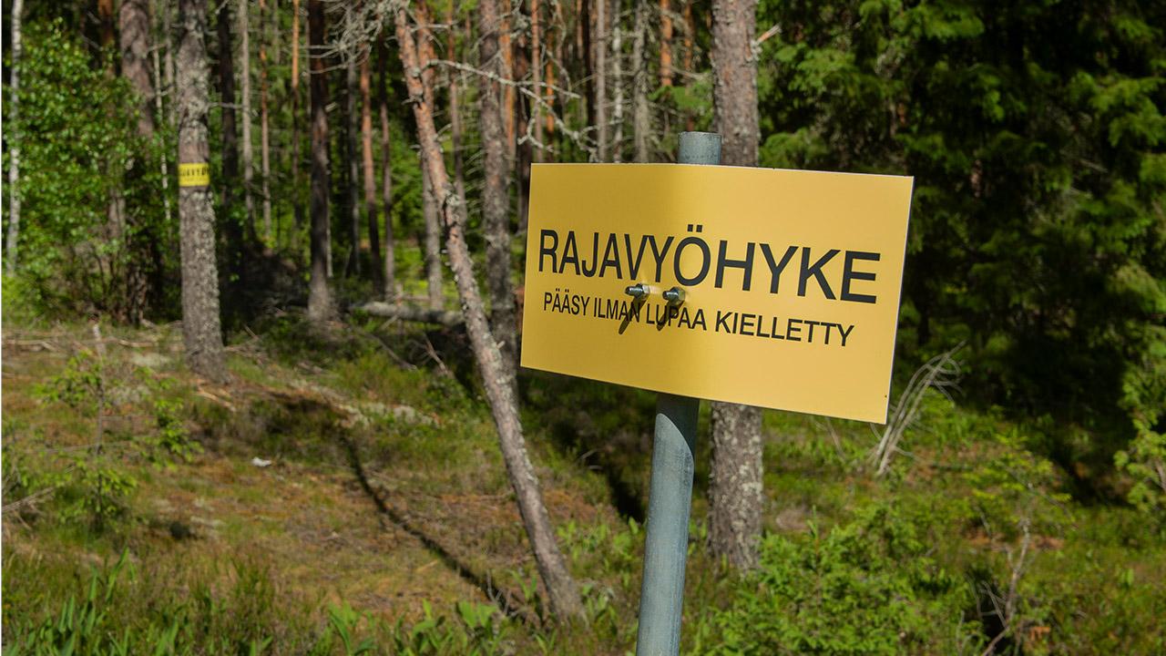 Rajavyöhyke-kyltti itärajan tuntumassa metsässä.