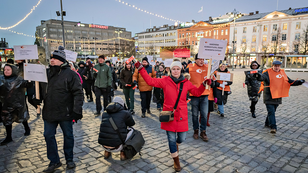 JHL:n järjestämä mielenosoitus Vaasassa. Kuvassa ihmisiä kyltteineen iltavalaistussa kaupungissa.