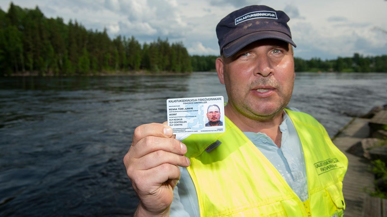 Kalastusmestari Tomi Menna näyttää kameralle kalastuslupakorttiaan.