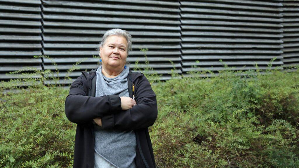 Henkilökohtainen avustaja Tarja Al Hanan seisoo pihalla ja katsoo kameraan.