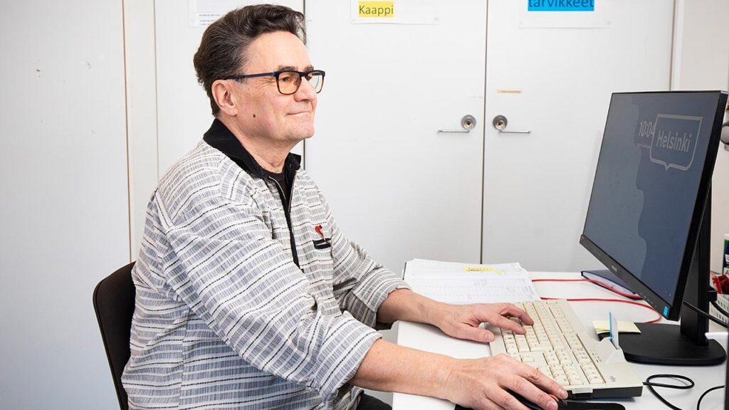 Työtä tekevä eläkeläinen Simo-Pekka Hämäläinen istuu päätteen ääressä toimistossa.