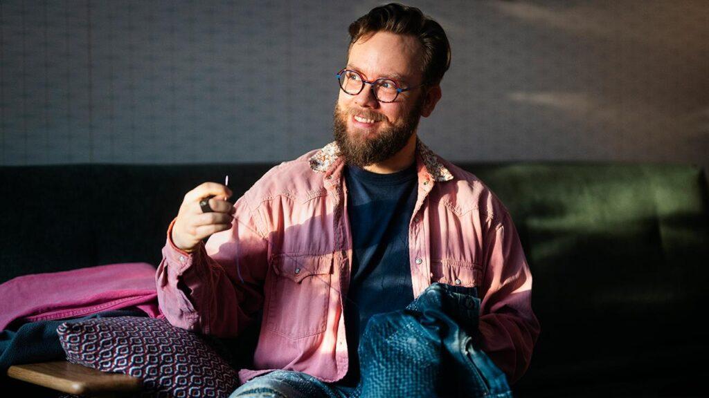 Käsityöaktivisti Niko Lindgren parsii farkkuja kotisohvallaan.