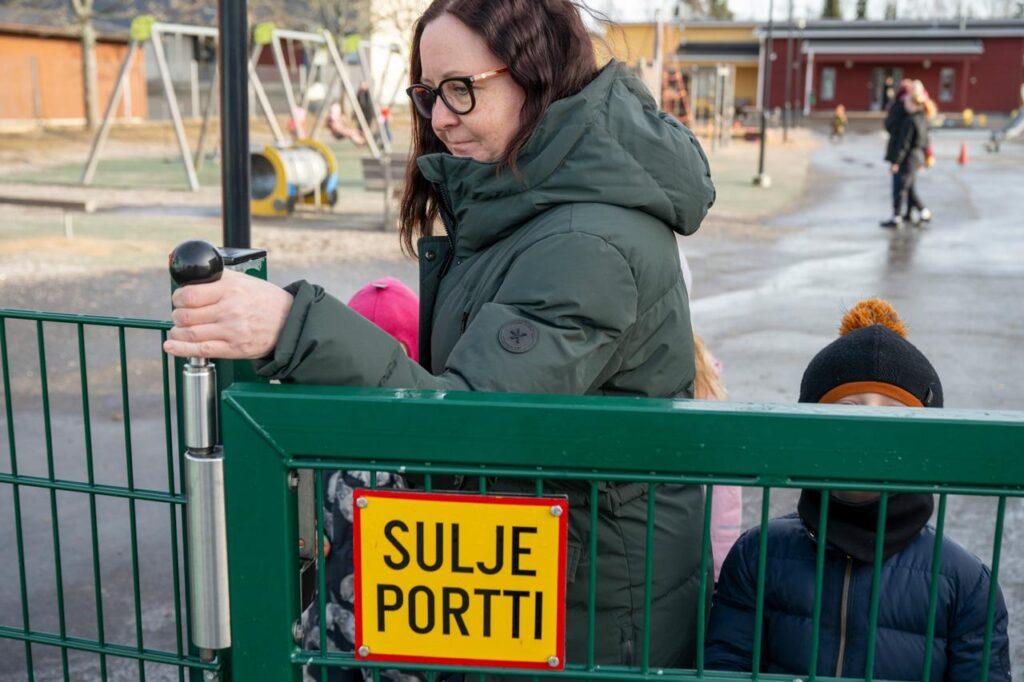 Varhaiskasvattaja sulkee portin päiväkodin pihalla.