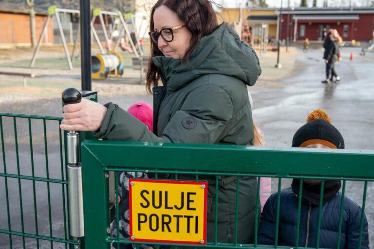 Varhaiskasvattaja sulkee portin päiväkodin pihalla.