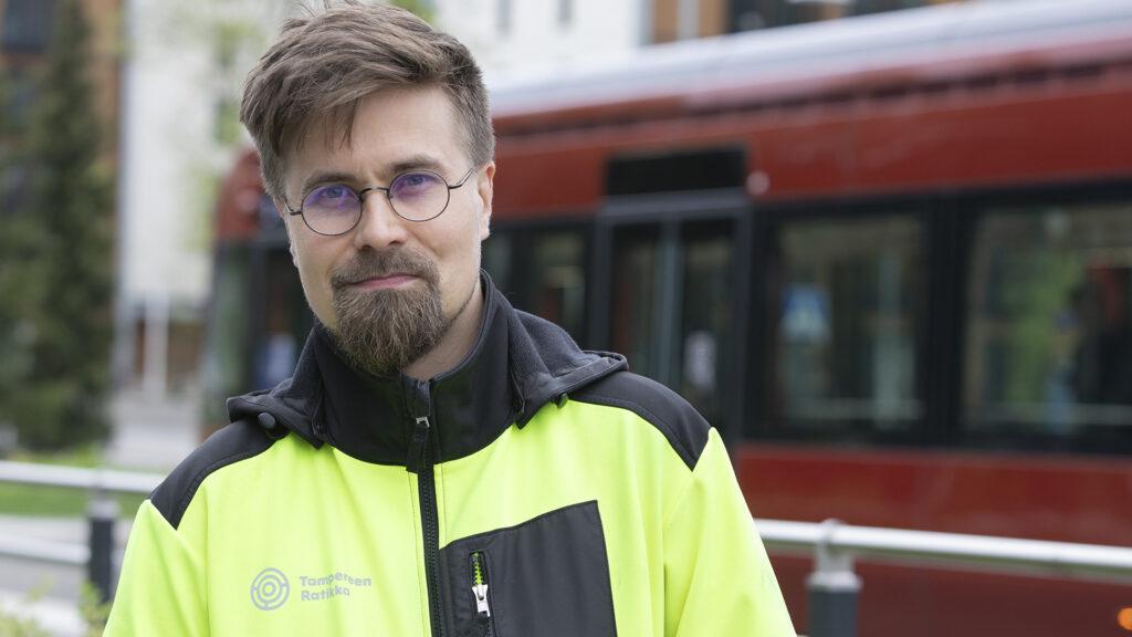 Tampereen Ratikan pääluottamusmies Viljami Vaskonen katsoo raitiovaunun edessä kameraan.