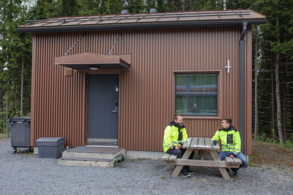 Tampereen Ratikan luottamusmiehet Jussi Aho ja Viljami Vaskonen istuvat pöydän ääressä puumökin pihalla.