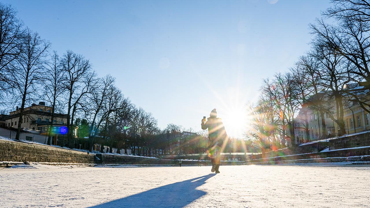 Alicia Iredale kävelee auringossa Turkua halkovan Aurajoen jäällä.
