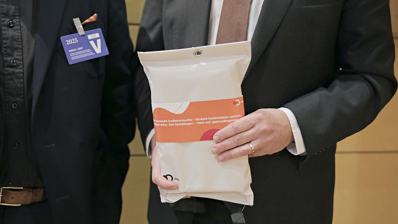 Keskustan puheenjohtaja Antti Kaikkosen kädet pitelevät sammutuspeitettä.