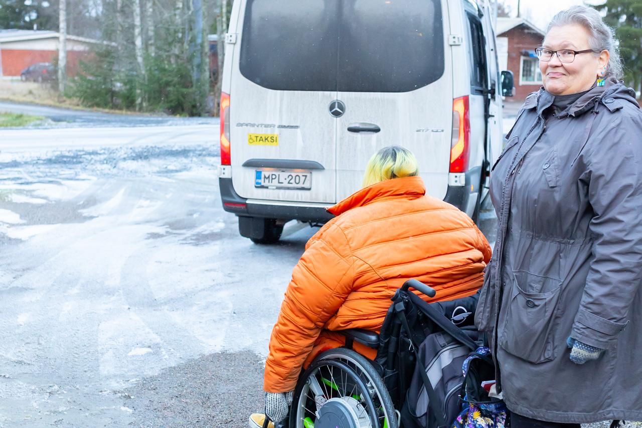 Henkilökohtainen avustaja työntää pyörätuolia