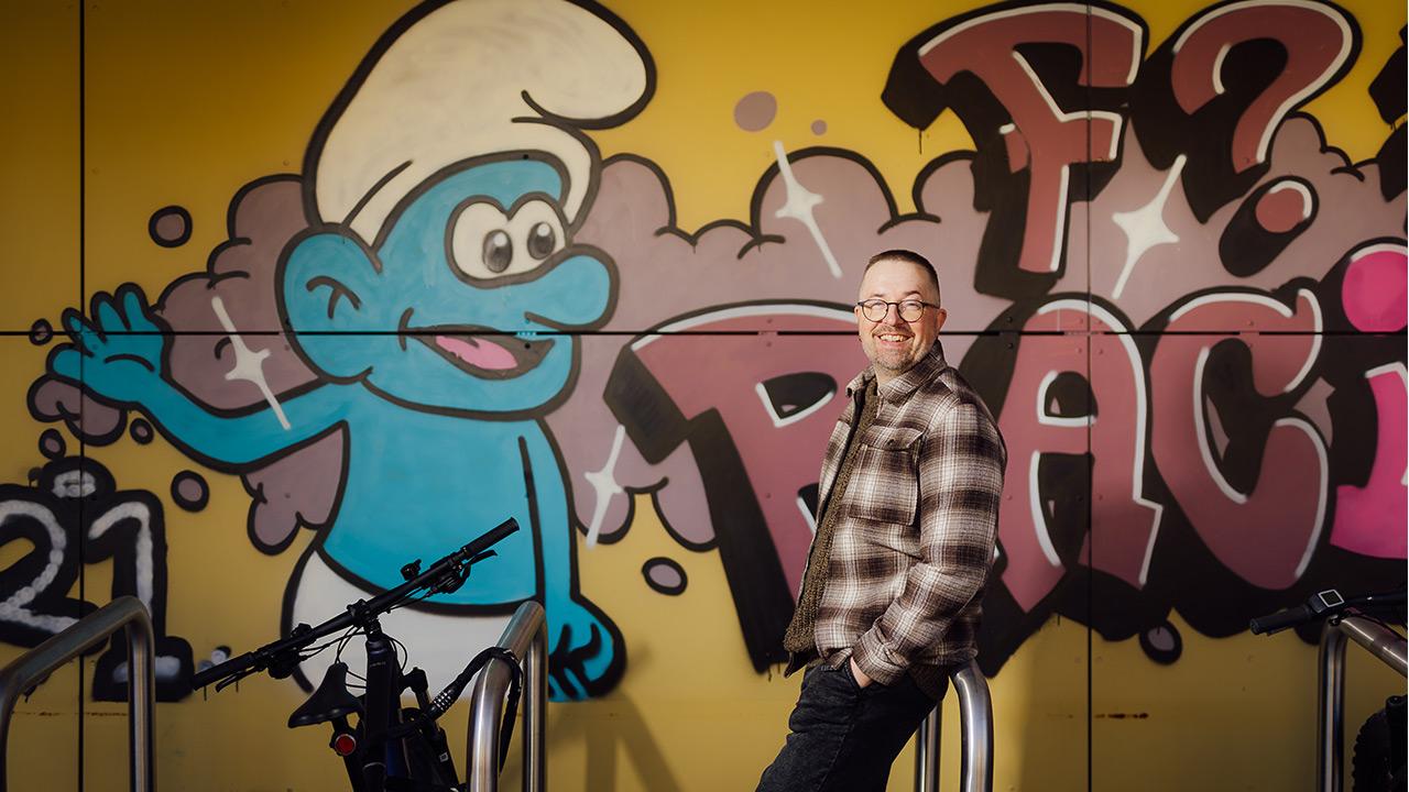 Koulunkäynninohjaaja Ville-Veikko Liekkinen nojaa graffitiseinään Kukkulan sairaalakoulussa Jyväskylässä.