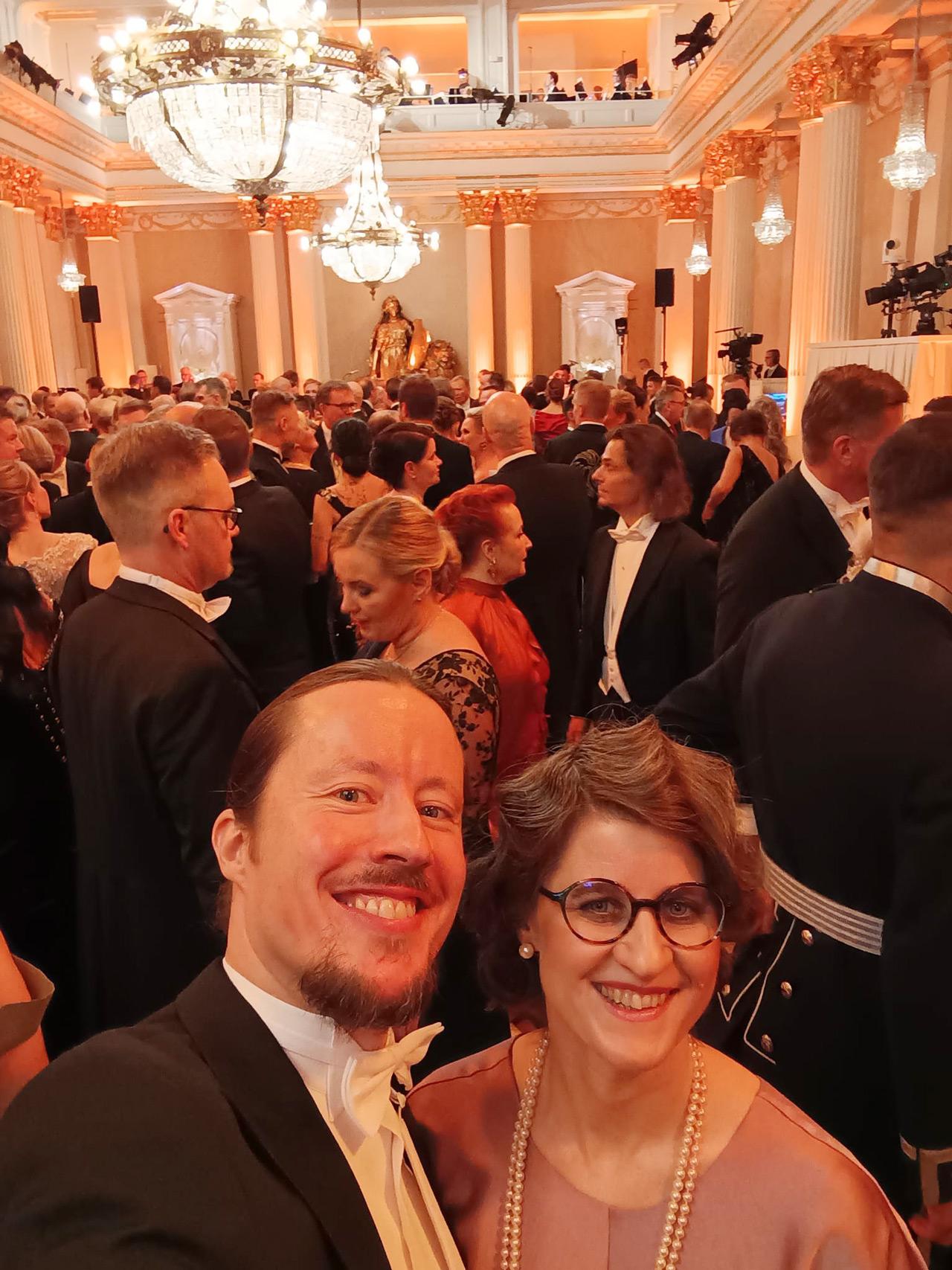 Kirjastonhoitaja Jutta Väyrynen ja hänen puolisonsa katsovat kameraan Linnan juhlissa Presidentinlinnassa itsenäisyyspäivänä 2025.
