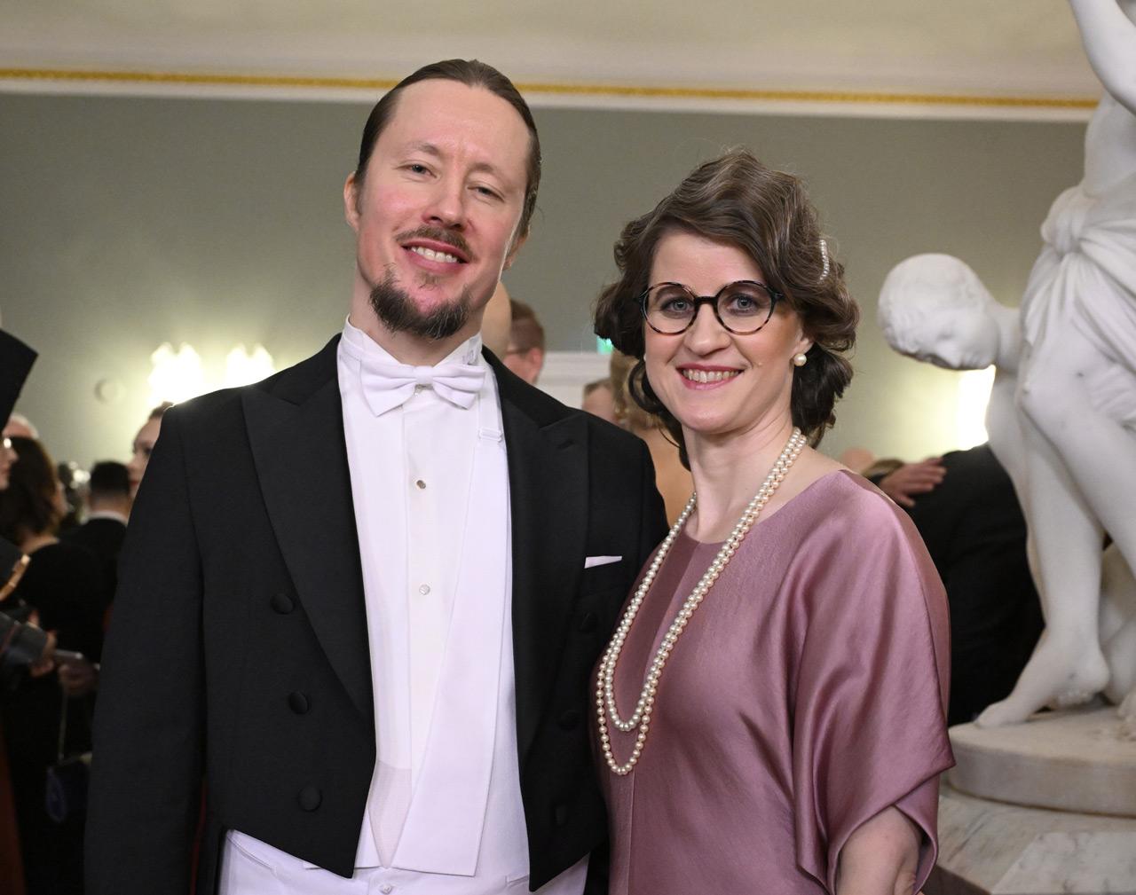 Kirjastonhoitaja Jutta Väyrynen ja hänen puolisonsa katsovat kameraan Linnan juhlissa Presidentinlinnassa itsenäisyyspäivänä 2025.