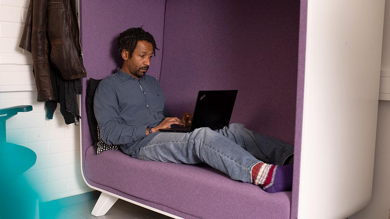 Yhteisöohjaaja Michael Fandi näpyttelee läppäriä violetilla sohvalla monikulttuurikeskus Gloriassa Jyväskylässä.