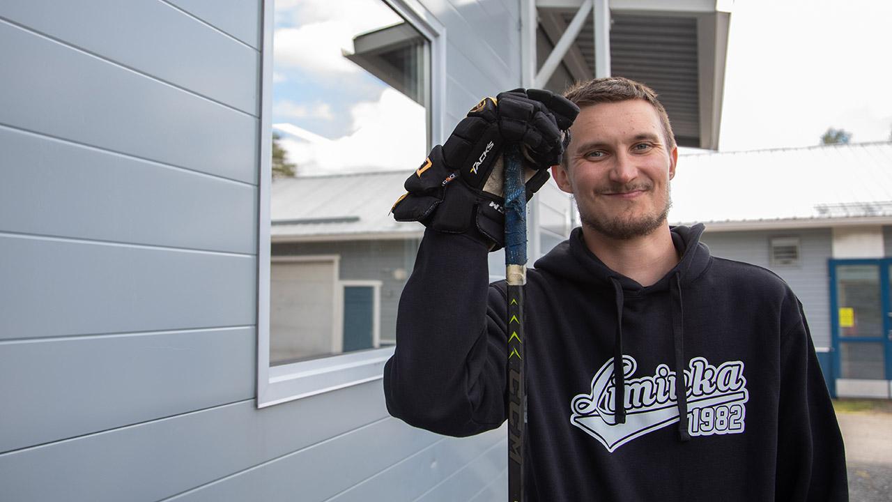 Liminkalainen Juuso Huovinen vilkuttaa jääkiekkohanska kädessään jäähallin edessä.