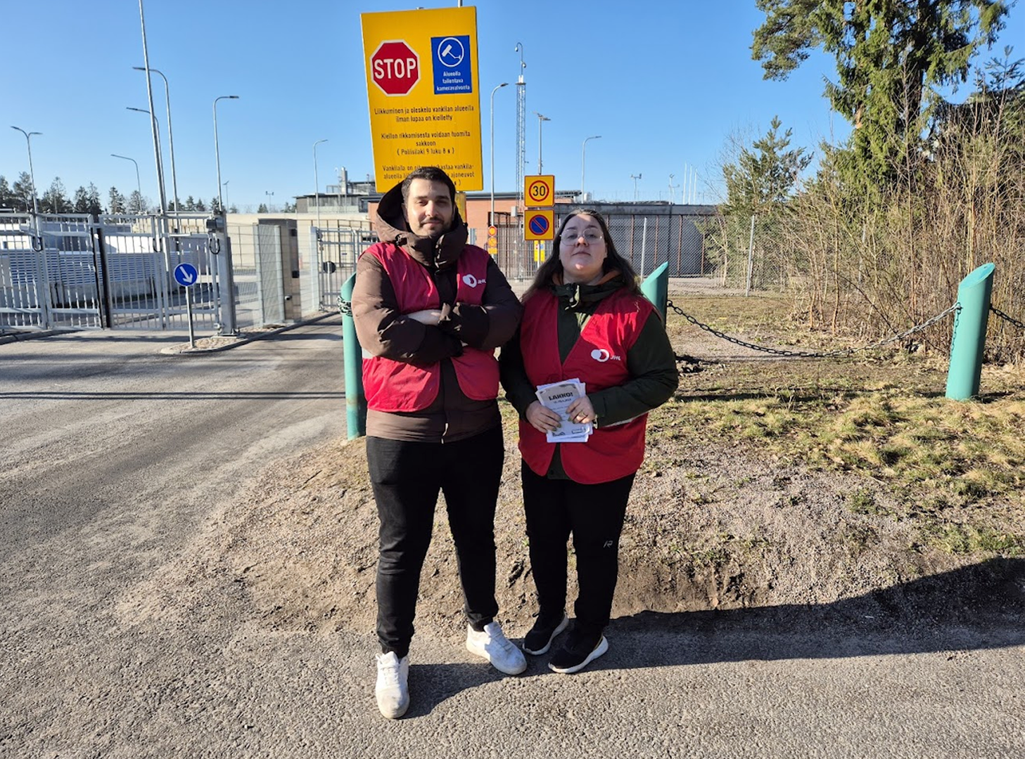 Vantaan vankilan työntekijät Derin Gomeyi ja Johanna Virtanen katsovat kameraan vankilan edustalla valtion virkamiesten lakkopäivänä.