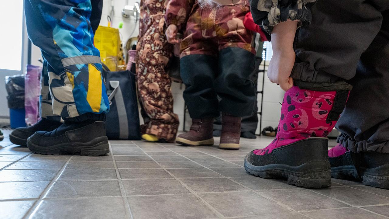 Lasten jalkoja päiväkodin lattialla.