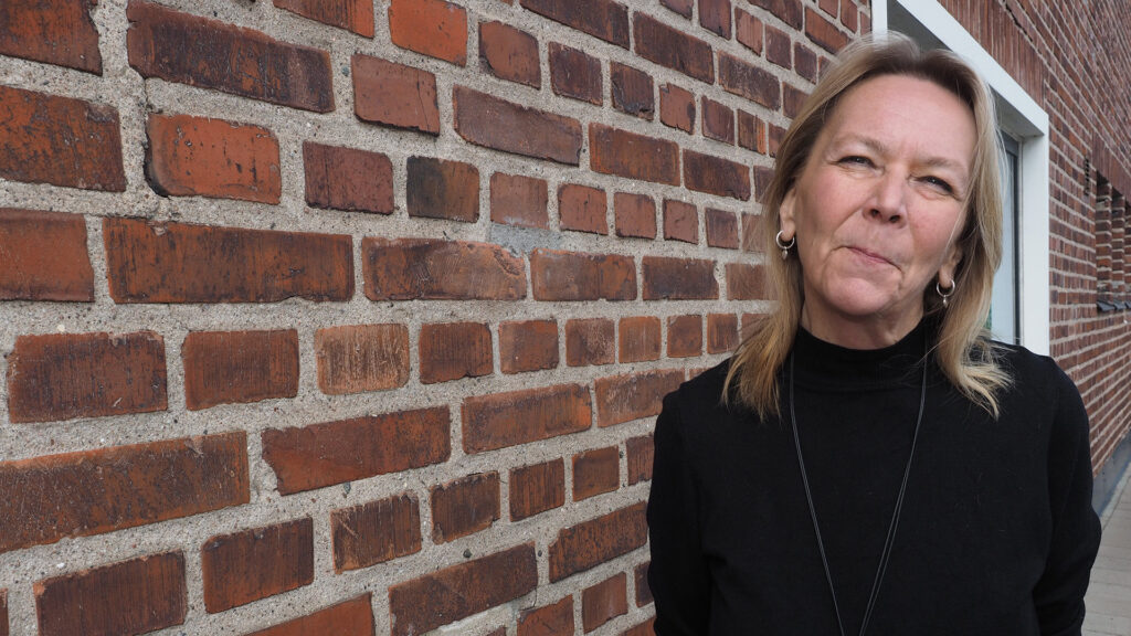 Tiina Liimatainen tiiliseinän vieressä.