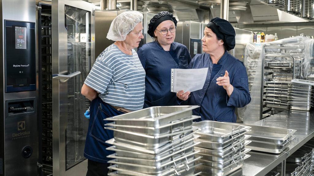 Vastuukokki Tuija Räsänen (vas.), dieettikokki Henni Immonen ja Tytti Saari käyvät läpi tulevan viikon ruokalistoja Espoonlahden aluekeittiössä.