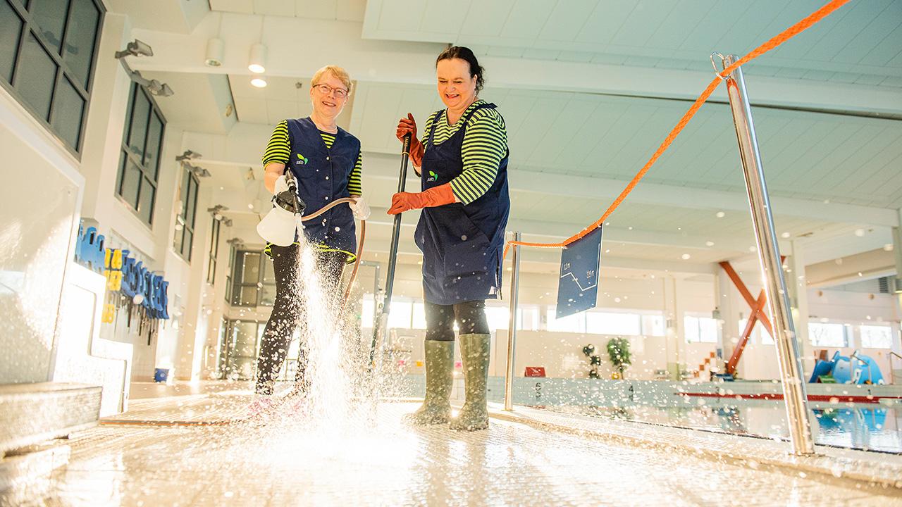 laitoshuoltajat Aila Patrakka ja Birgitta Halsvaha siivoavat uimahallia