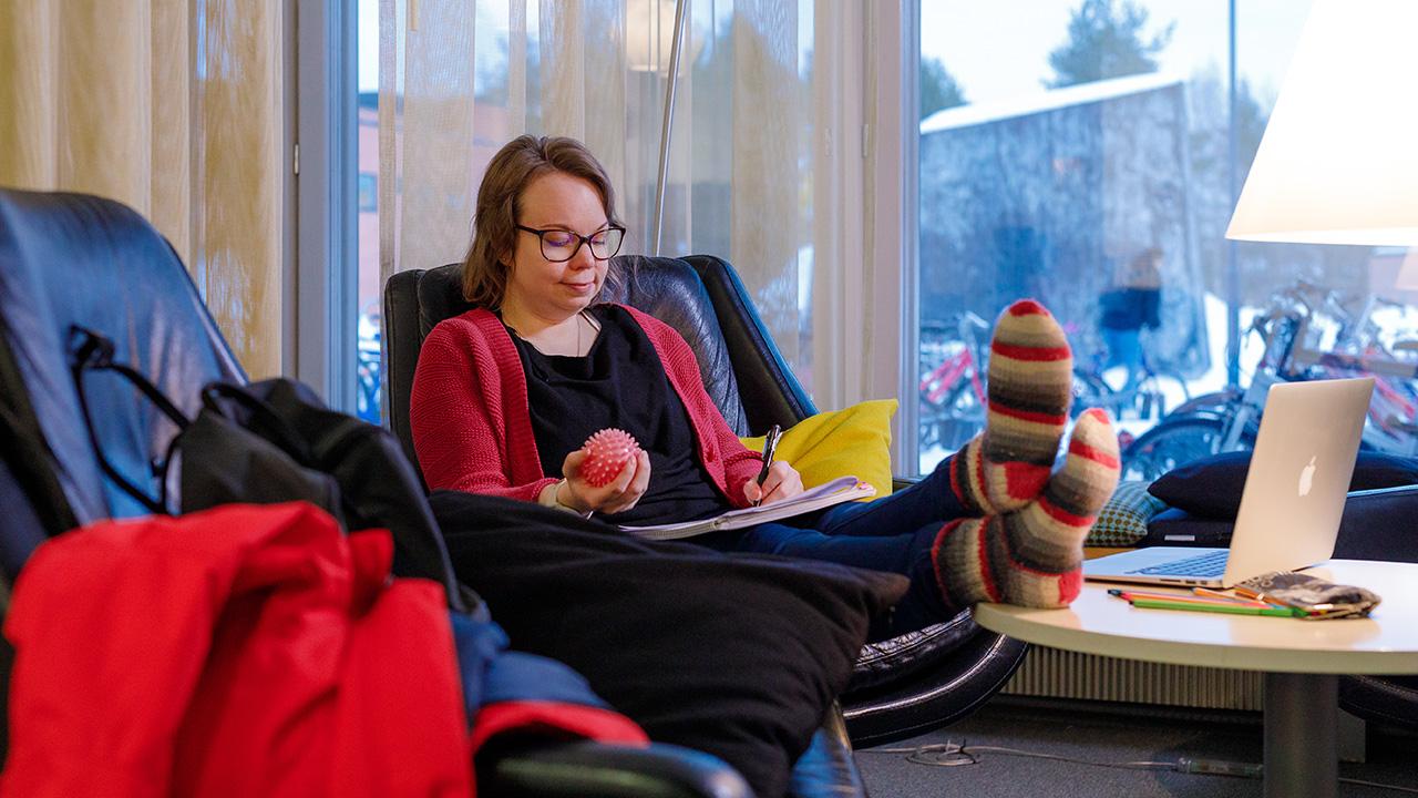 Kasvatustieteiden maisteri Hanna-Mari Nevalainen istuu Joensuun yliopiston kirjastossa stressipallon ja tenttikirjan kanssa.