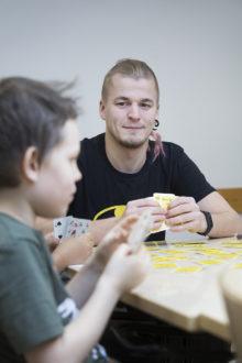 Iltapäiväkerhon ohjaaja Oscar Maukkonen pelaa lasten kanssa korttia.
