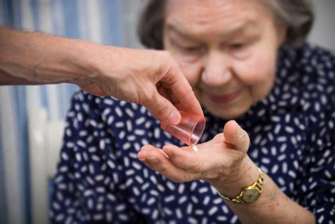 En äldre kvinna får ett piller.