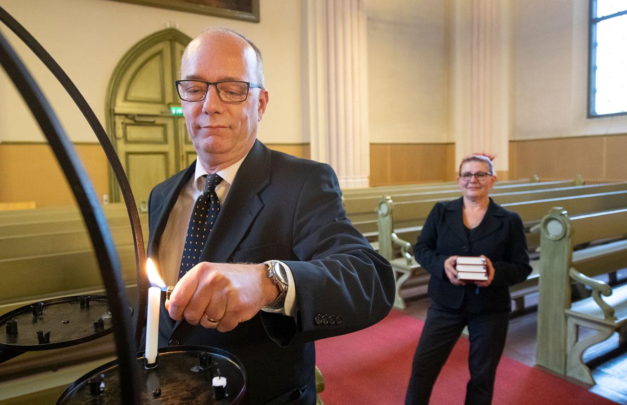 Christer Viksten sytyttää kynttilää lähetyskynttelikköön, Maria Viksten odottaa virsikirjojen kanssa kauempana.