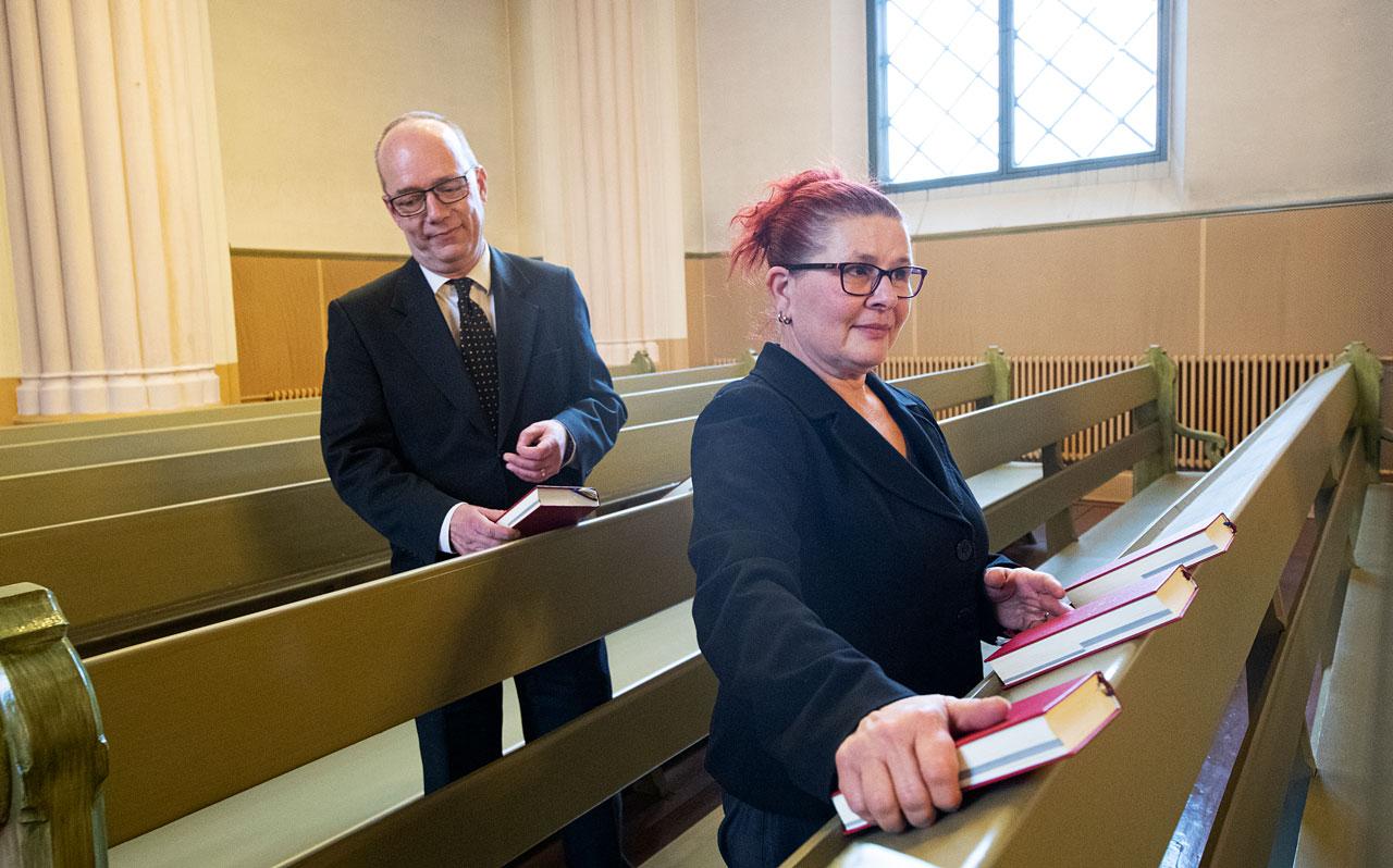 Christer ja Maria Viksten jakavat virsikirjoja kirkon penkkeihin.