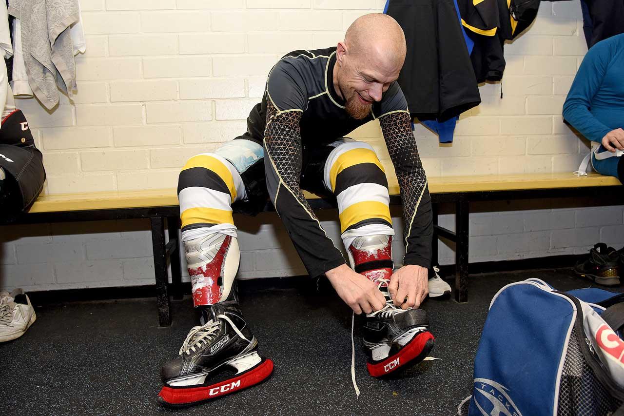 Los Bombers -joukkueessa jääkiekkoa pelaava JHL:läinen Tony Hästbacka kiristää luistimia pukuhuoneessa.