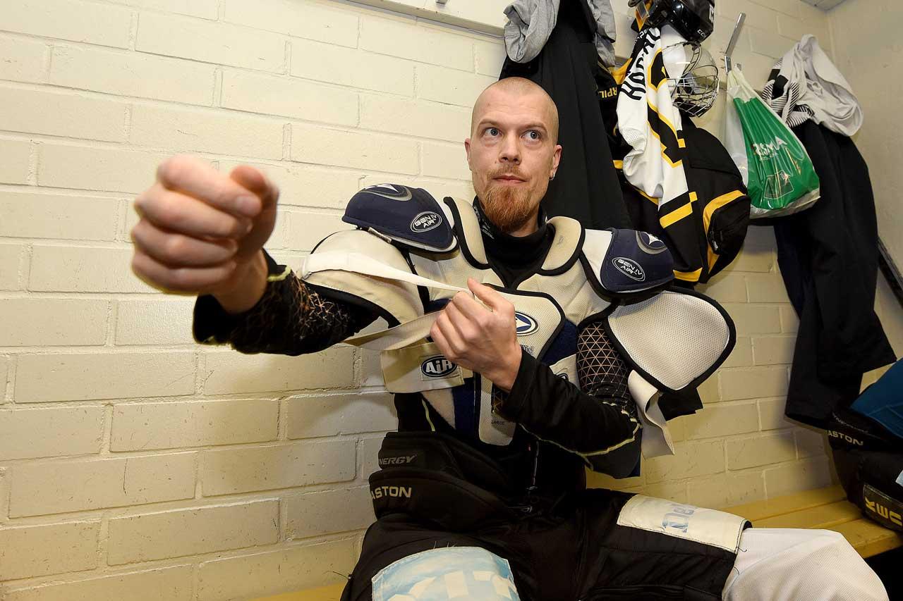 Los Bombers -joukkkueessa jääkiekkoa pelaava JHL:läinen Tony Hästbacka vetää päällensä olkasuojaimet pukuhuoneessa.