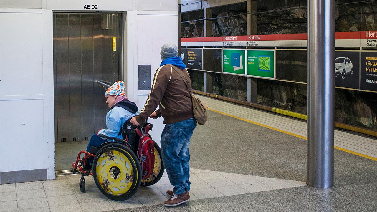 avustaja auttaa vammaista pyörätuolissa