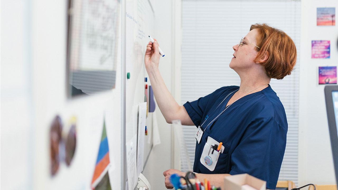Etelä-Karjalan keskussairaalan palveluesimies Minna Junni kirjoittaa työkalenteria työhuoneessaan.