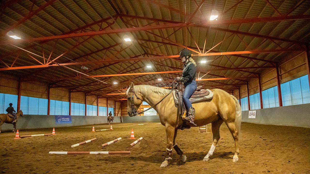 Lännenratsastaja Merita Korhonen ratsastaa hevosella maneesissa.