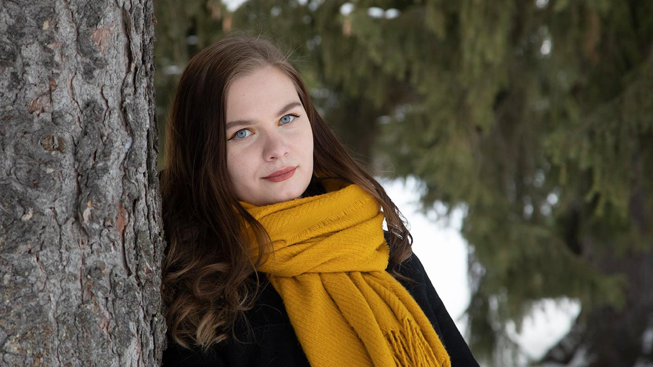 Opiskelija, Oulun Setan työntekijä Milla Heino nojaa puuhun lumisessa puistossa Oulussa.