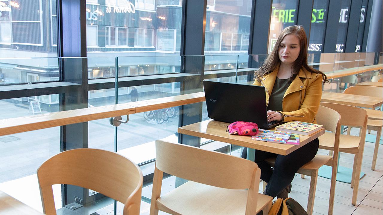 Opiskelija, Oulun Setan työntekijä Milla Heino näpyttelee läppäriä kahvilassa.